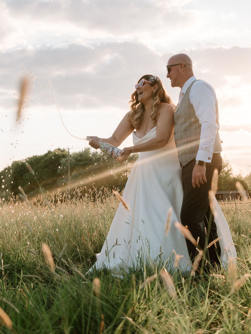 Romantic couple walks through a sunlit meadow at  Tywning Park during golden hour.