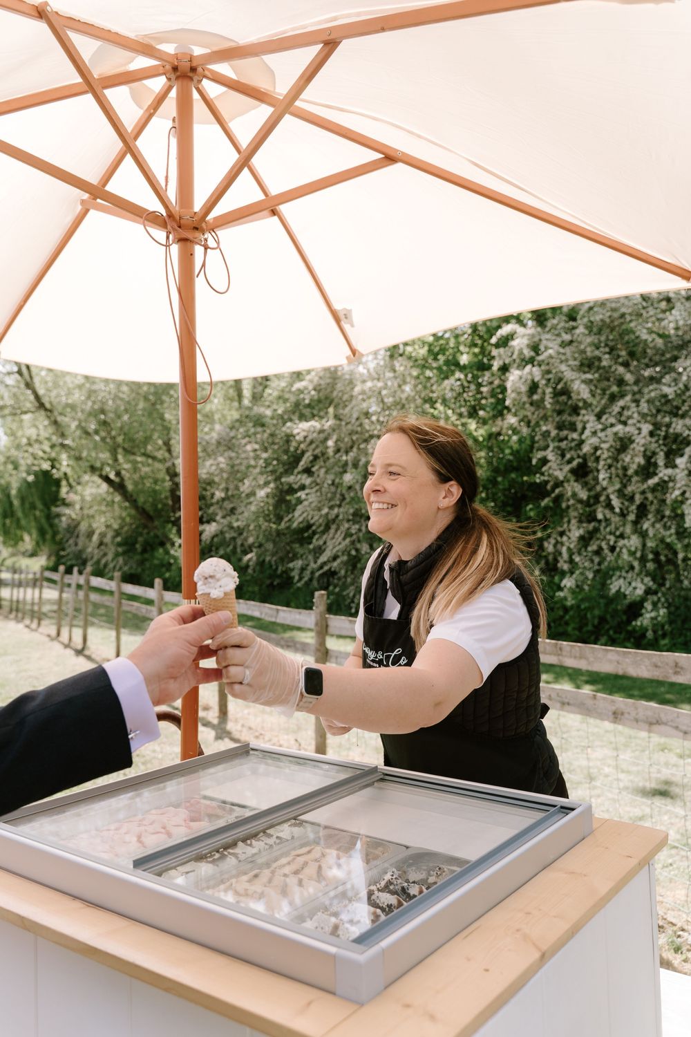 A person enjoying drinks under peach-colored patio umbrellas at an outdoor bar area.