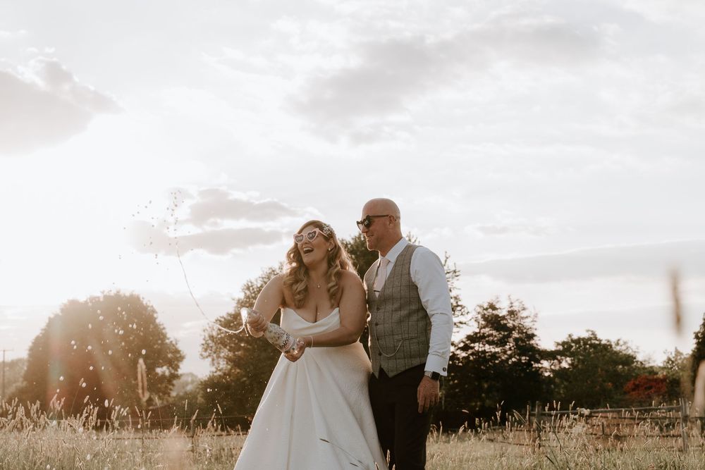 Worcestershire & Cotswold Newlyweds share an intimate moment in a sunlit meadow during golden hour.