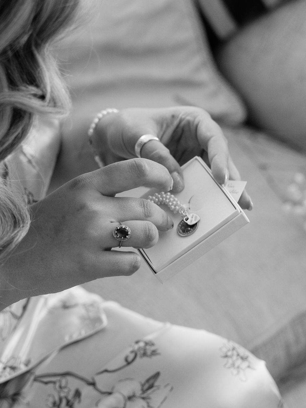 Black and white close-up of hands holding delicate jewelry and accessories.