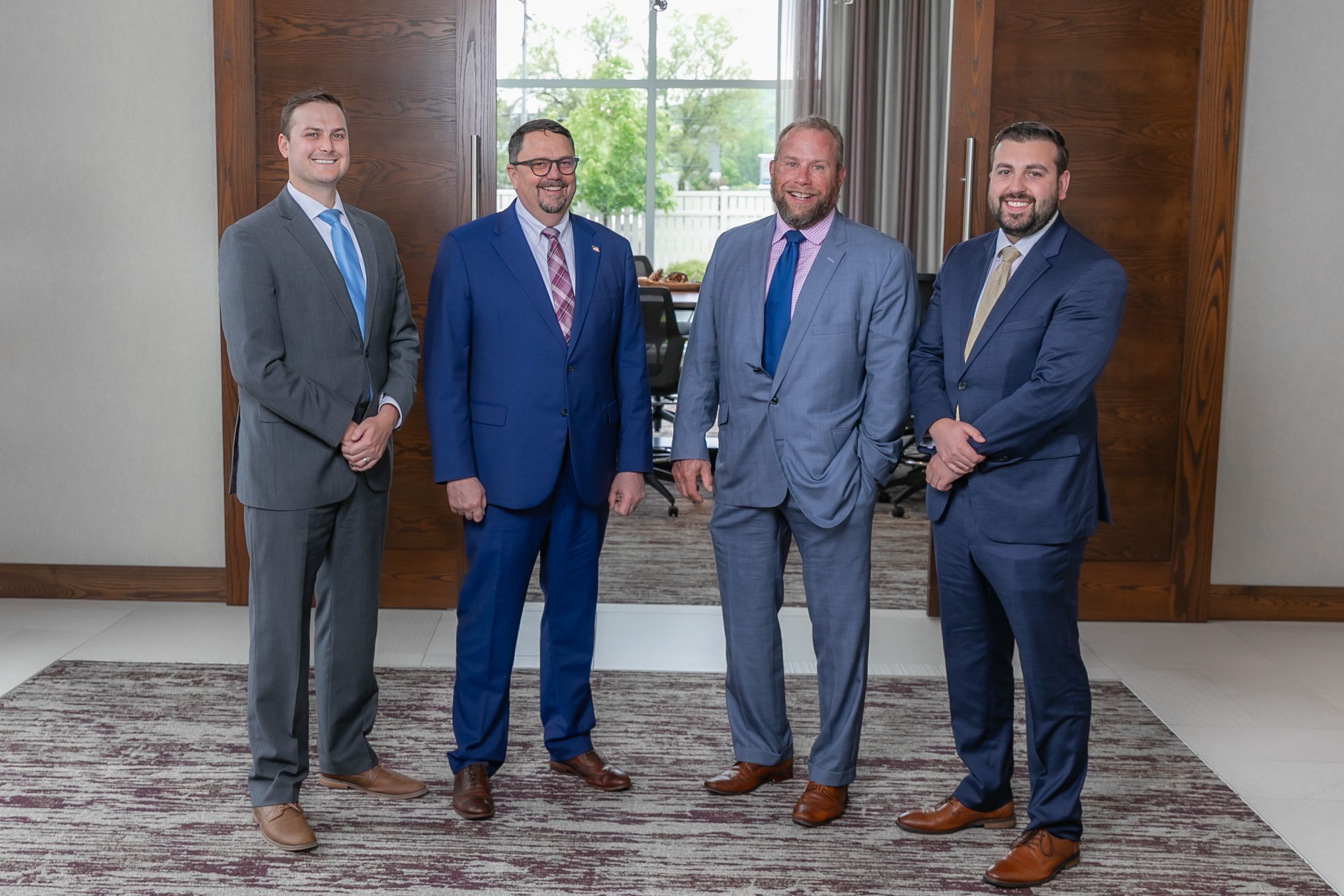 A group of groomsmen in blue and gray suits pose together at a wedding venue.