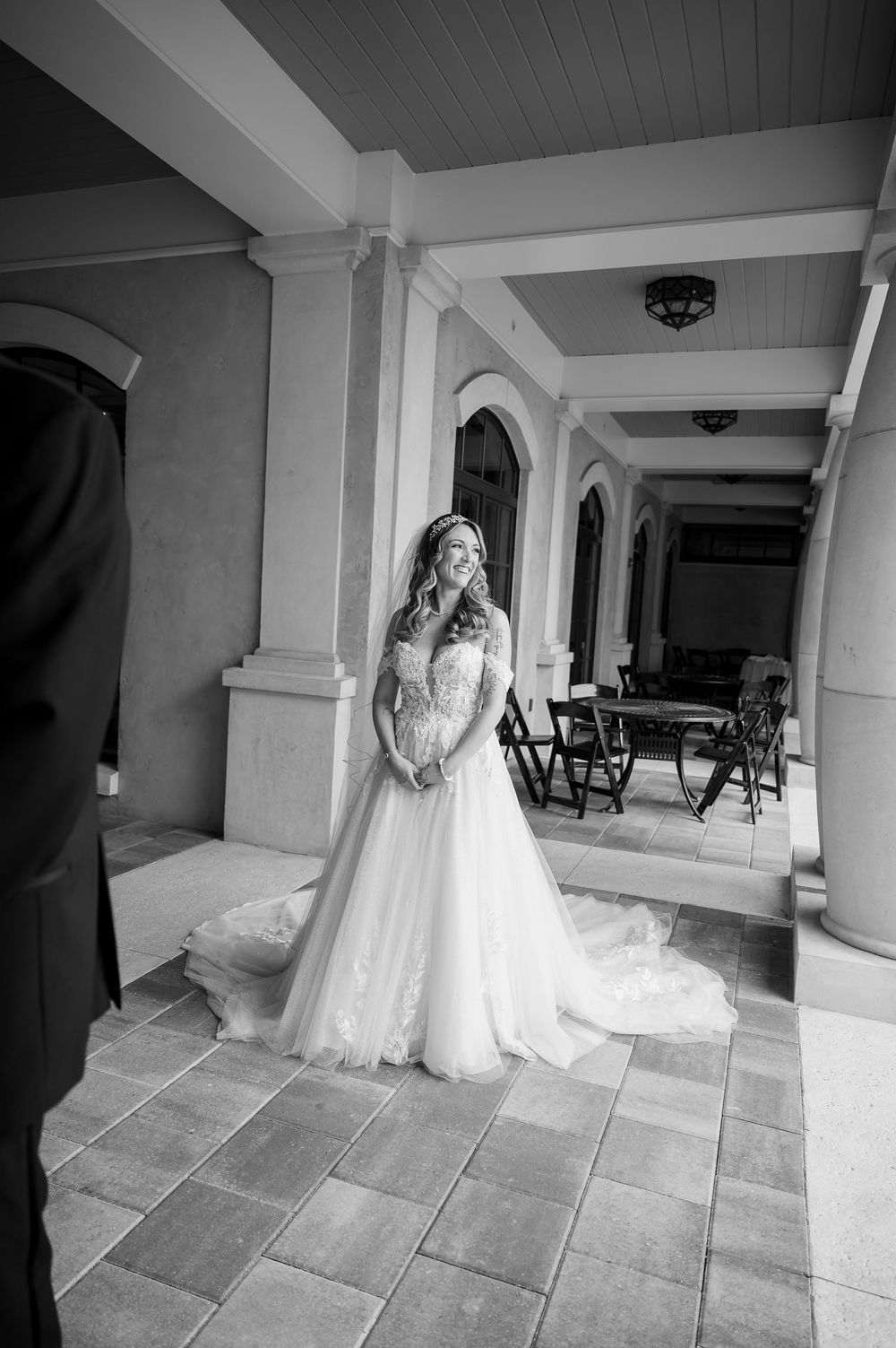 Black and white series of a bride walking along a covered outdoor portico.