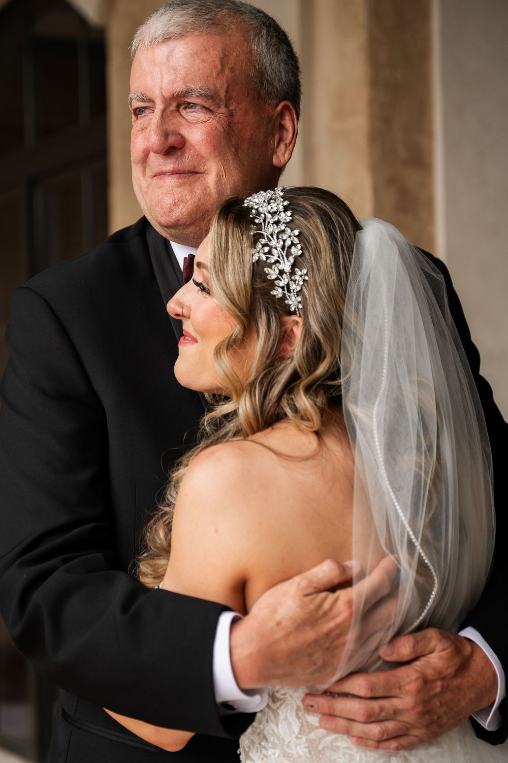 Intimate embrace captured between bride in white dress and father during wedding day first look.