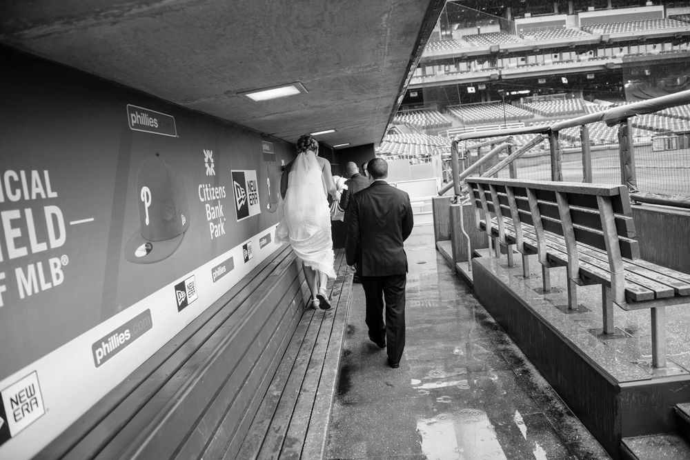 Vintage black and white photograph showing a bride walking on the benches of the Phillies home dugout.