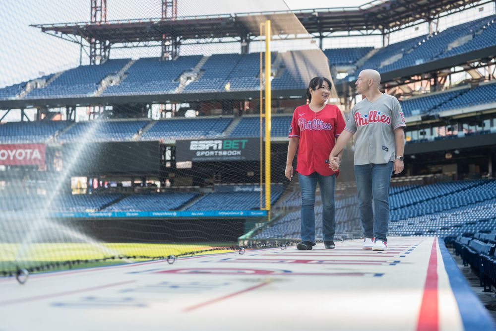 Couple walking along the top of the Phillies dugout in Citizens Bank Park with the stadium seating in the background