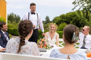 Brudepar og bryllupsgjester i prat og mingling i hagen