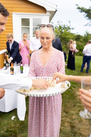 Bryllupsgjest serverer fingermat. Gjester strekker hendene for å forsyne seg.