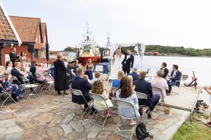 Brudeparet står på brygga og løfter hendene i været. De er akkurat nygift!