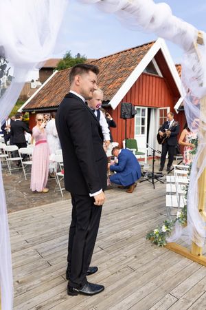 Brudgommen står på brygga og venter på bruden. På armen har han sønnen.