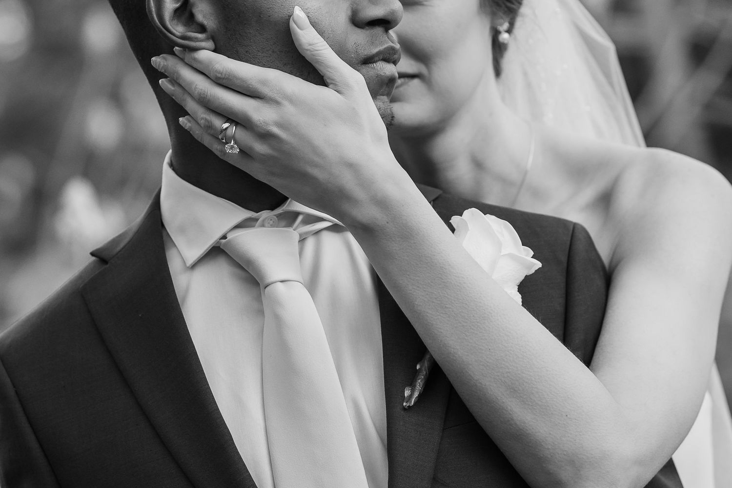 Close-up black and white emotional wedding moment with hands covering faces.