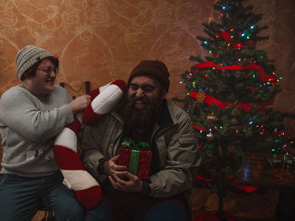 Festive scene by Christmas tree with holiday decorations and wrapped gifts.