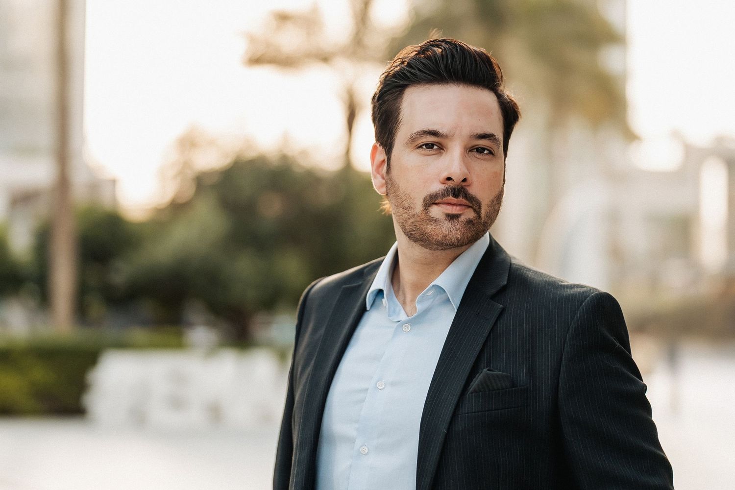 Celebrity portrait of Mikaal Zulfiqar wearing black suit at sunset