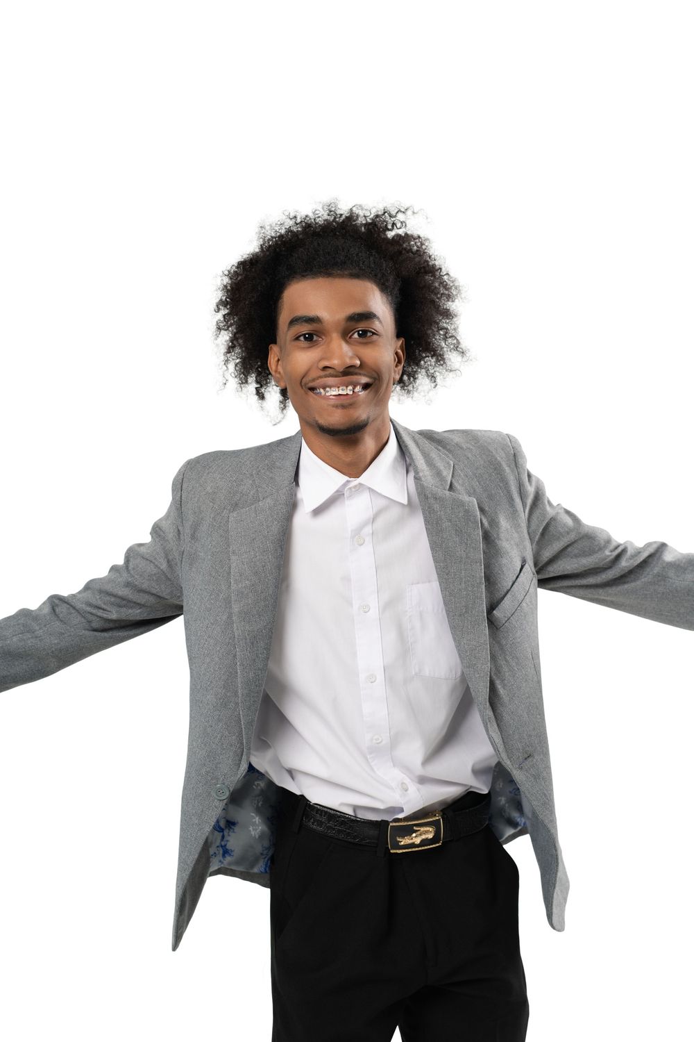 A person in a gray blazer and white shirt dances expressively with outstretched arms against a white background.