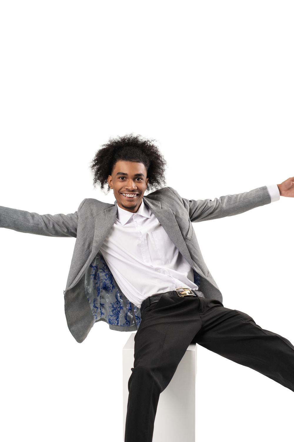 A person in a grey blazer and white shirt jumps joyfully with arms outstretched against a white background.