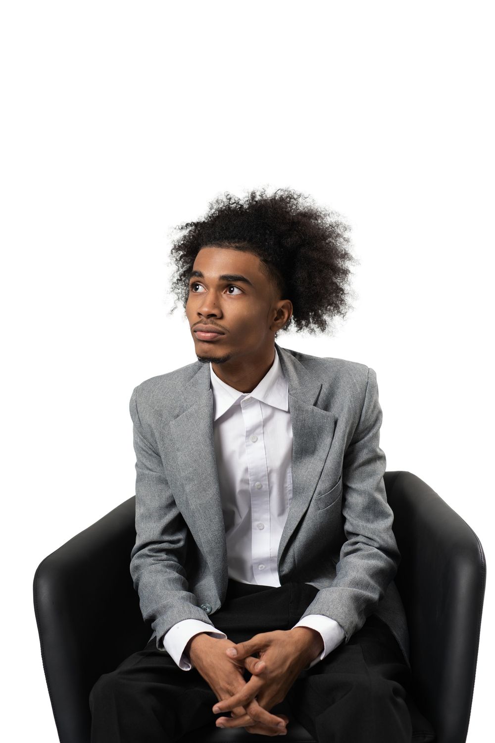 A person in a gray suit jacket and white shirt sits in different poses on a black chair against a white background.