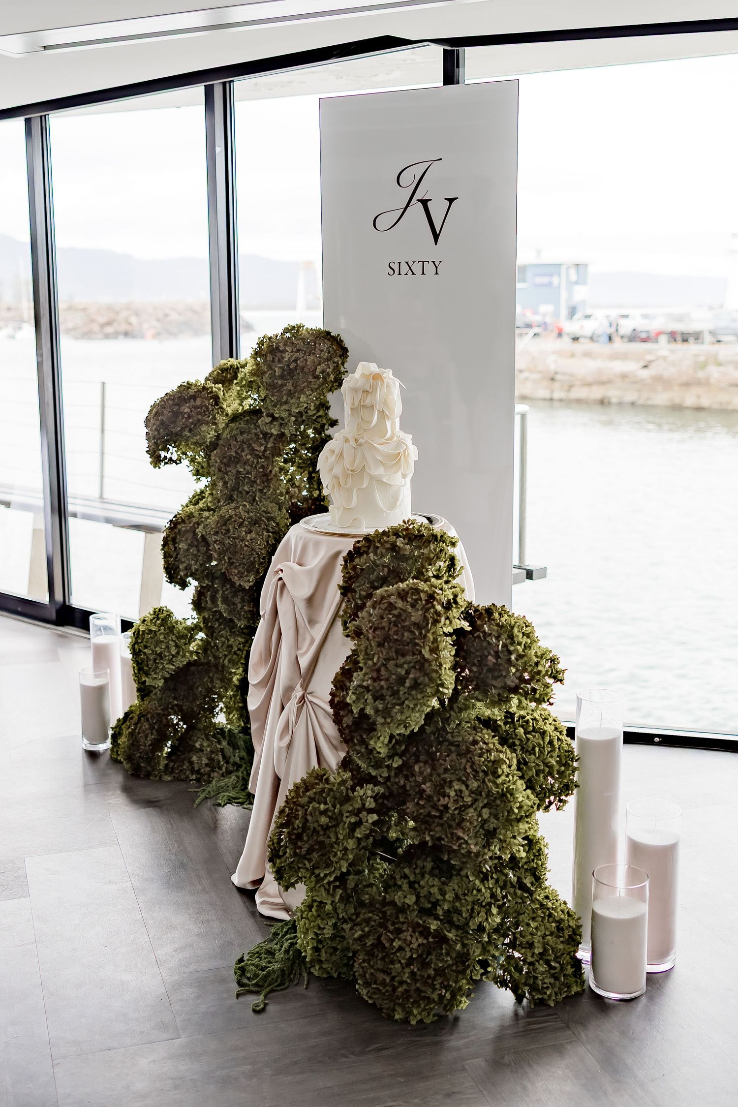 Classical white statue displayed next to a large green moss-covered wall installation in a modern gallery space.