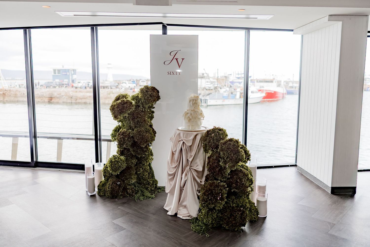Modern event space with large windows, white decor, and topiary arrangements creating an elegant atmosphere.