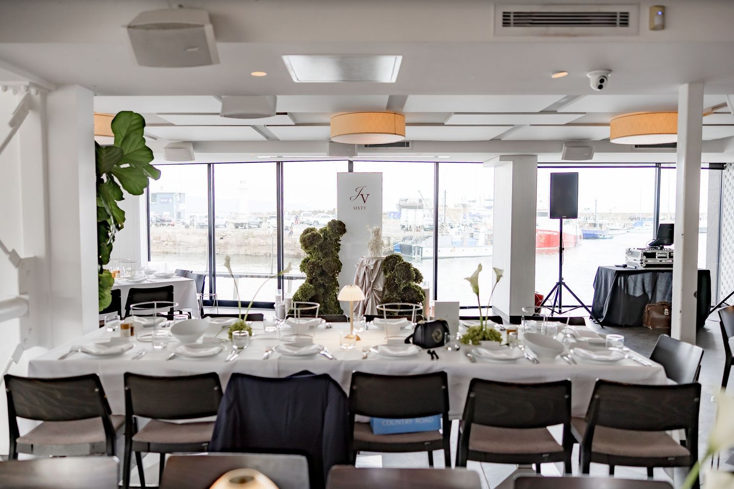 Modern open office space with white desks, chairs, and large windows offering natural light and city views.