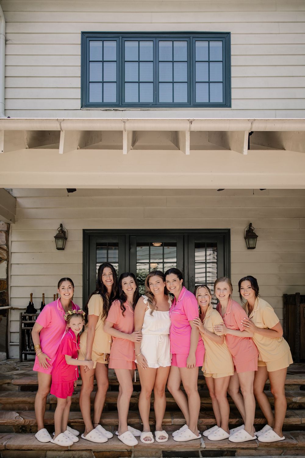 Wedding party wearing pink and peach robes lined up showing their slippers in a fun group photo.
