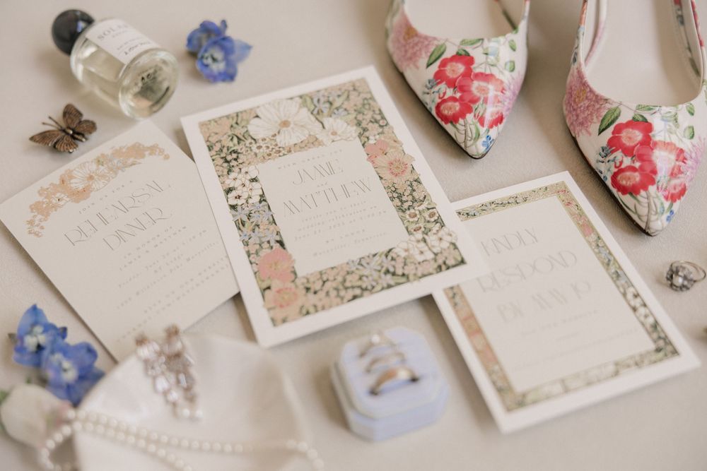 Wedding stationery and invitations with delicate floral designs and blue accents laid out on a surface.