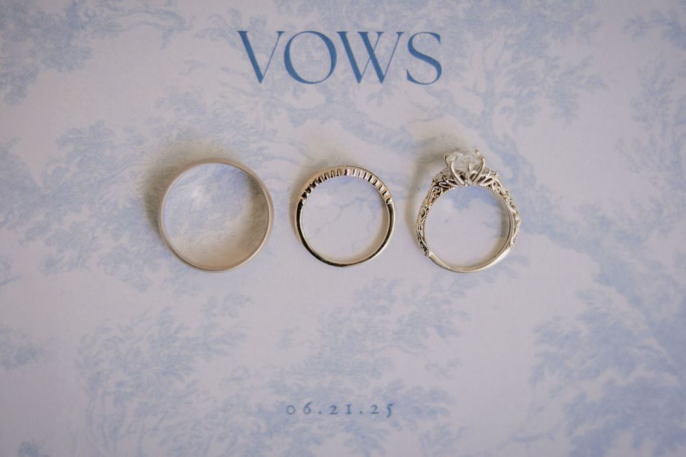 Wedding rings and vows book arranged on light blue textured background.