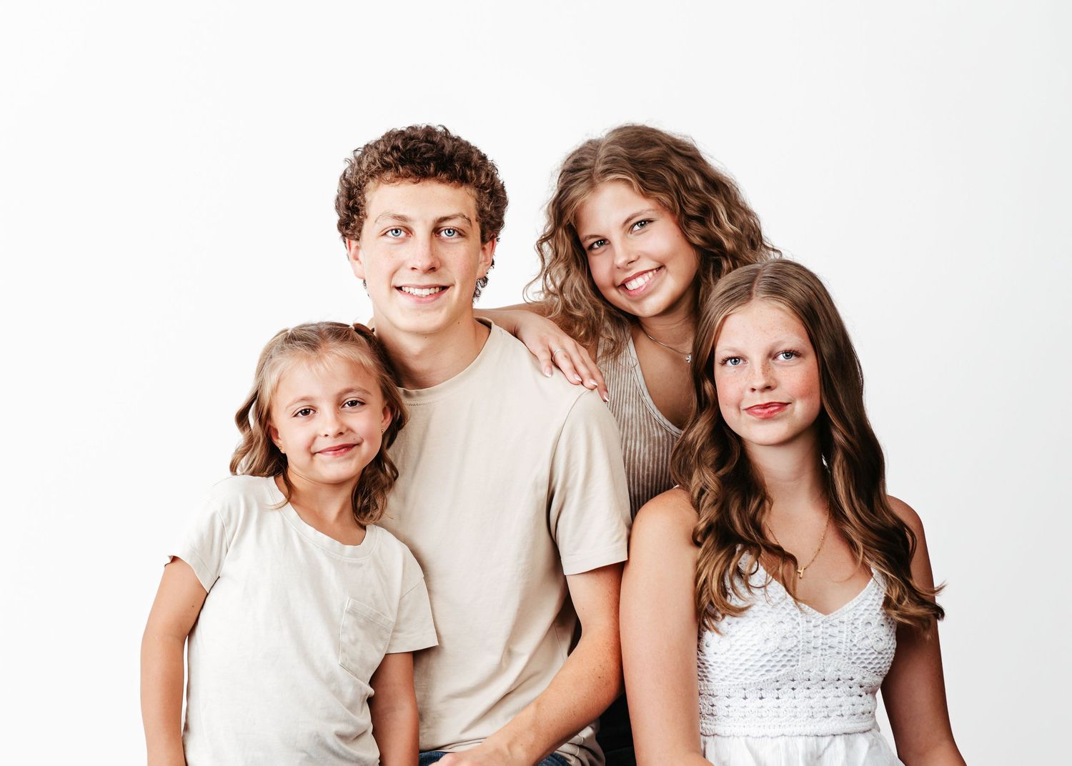 A family group in casual white clothing poses together against a white background.