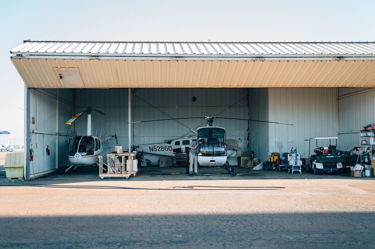 Row of modern aircraft hangars with metal roofing under clear blue skies.