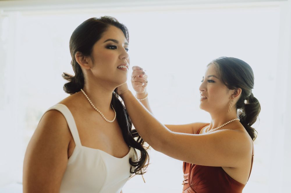 Wedding party members helping with final preparations in a bright room.