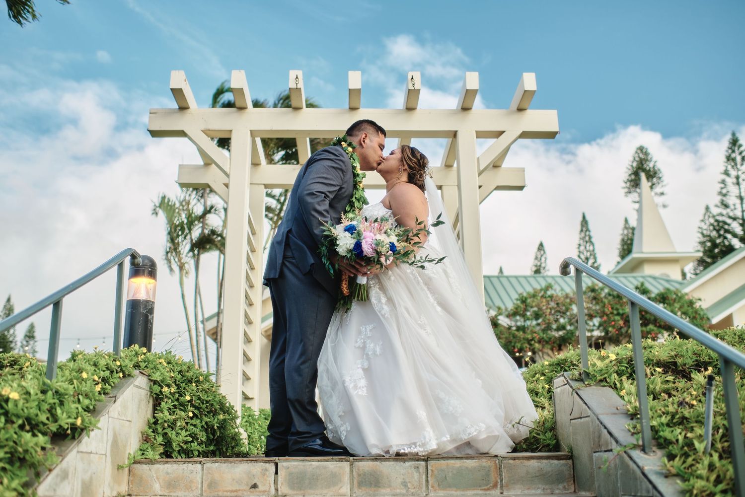 Wedding ceremony taking place under a white gazebo with ornate architectural details.