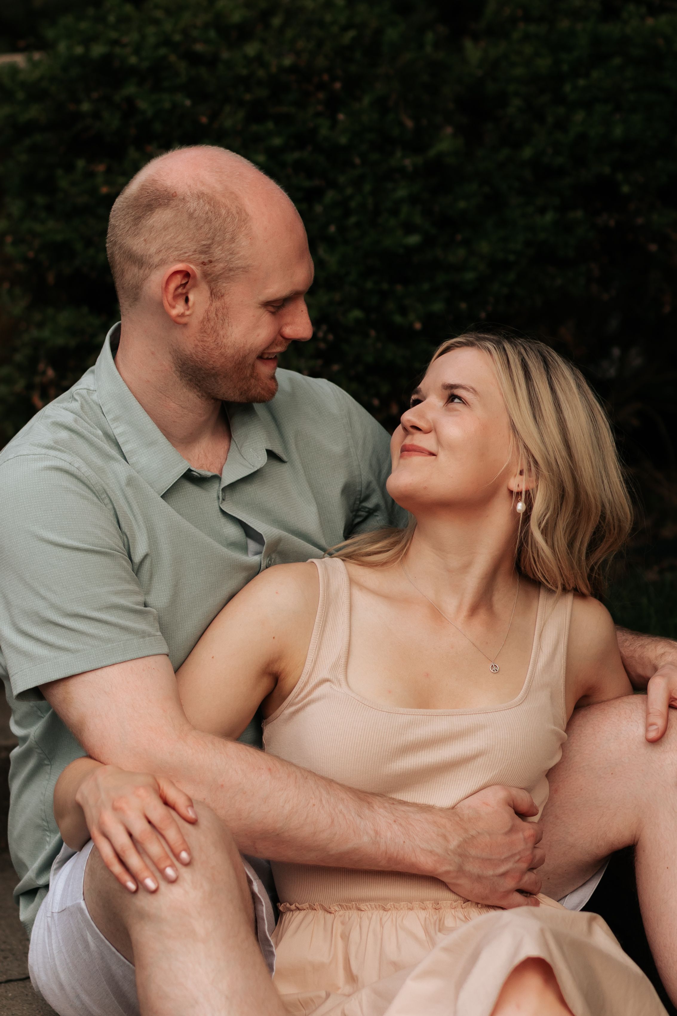 Romantic couple in casual attire share intimate moments in an outdoor photoshoot with natural lighting.