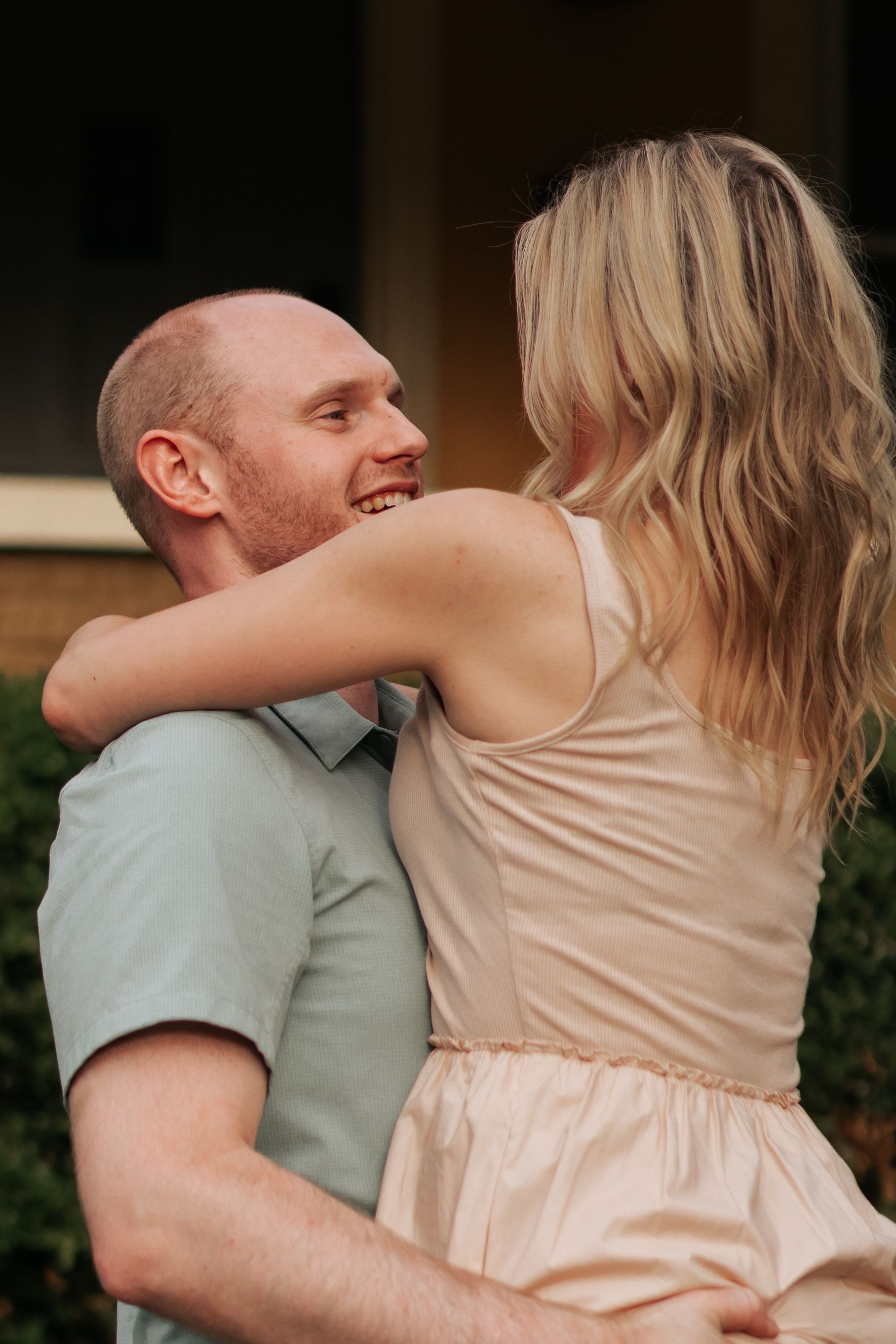 Couple embraces tenderly while wearing light colored clothing during a romantic outdoor portrait session.