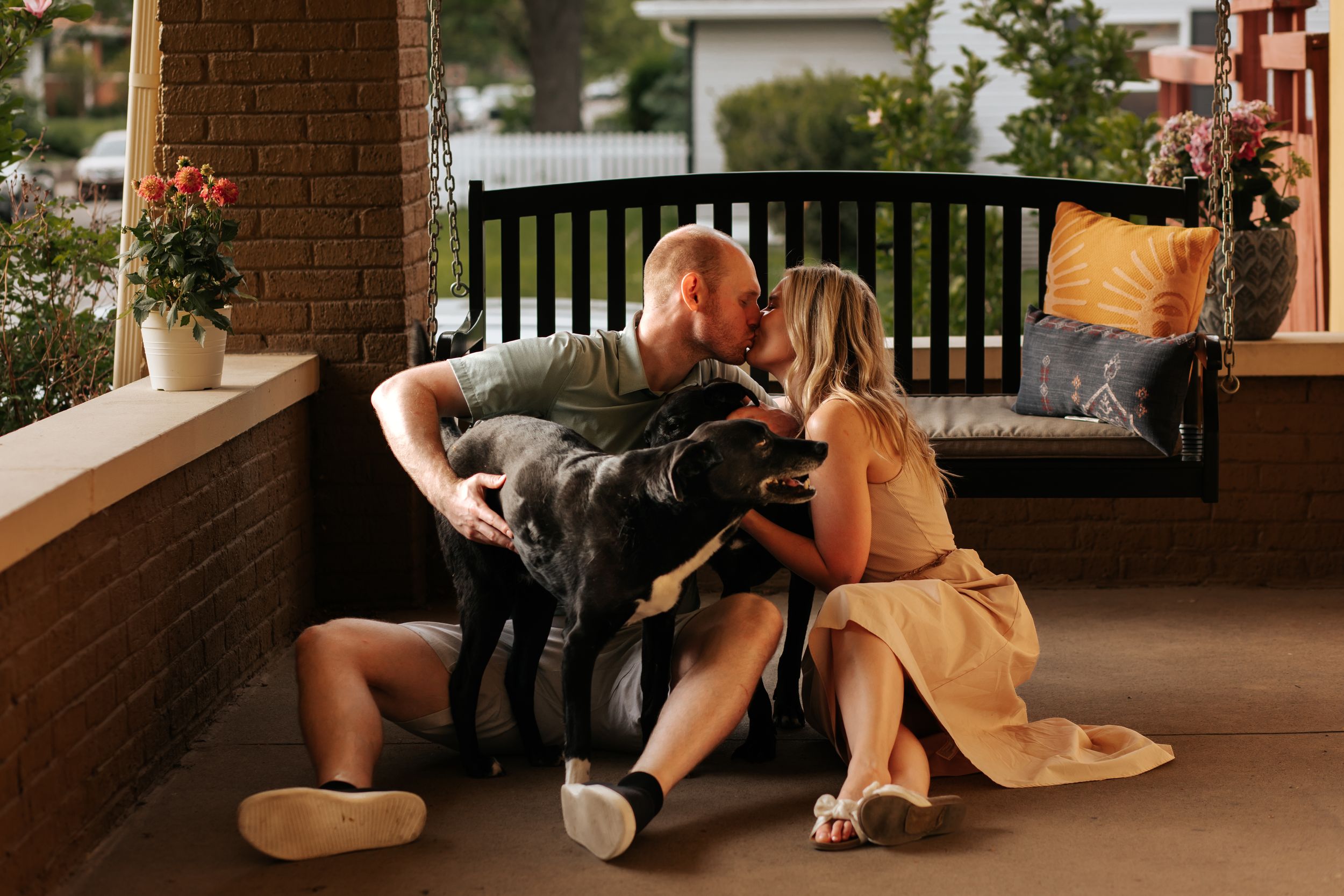 People and their dog enjoy quality time together on a brick porch during golden hour.