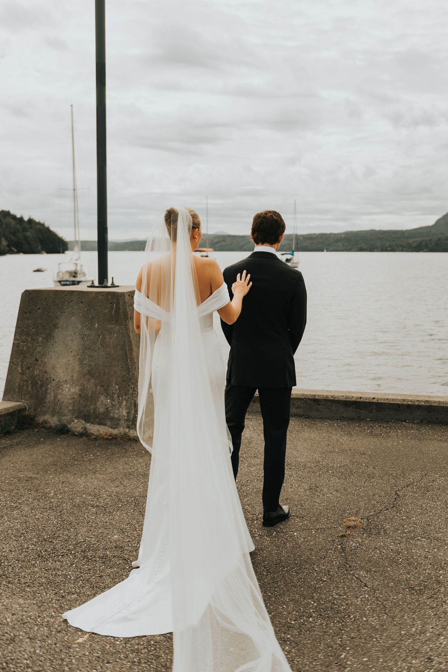 Bride and groom share a romantic moment at a waterfront overlook on their wedding day.