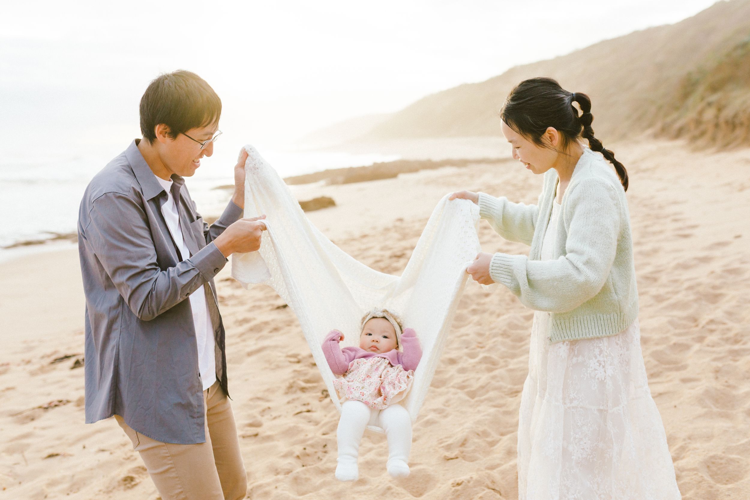 A couple in formal attire shares a romantic moment together on a sandy beach at sunset.