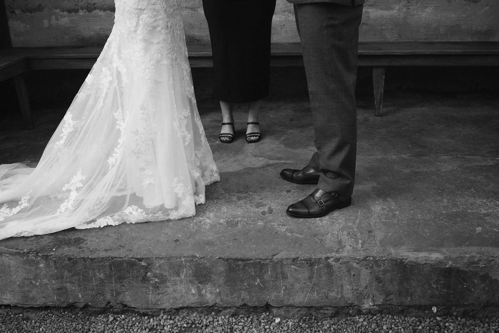 Black and white photo of a wedding ceremony in a covered outdoor venue with guests watching.