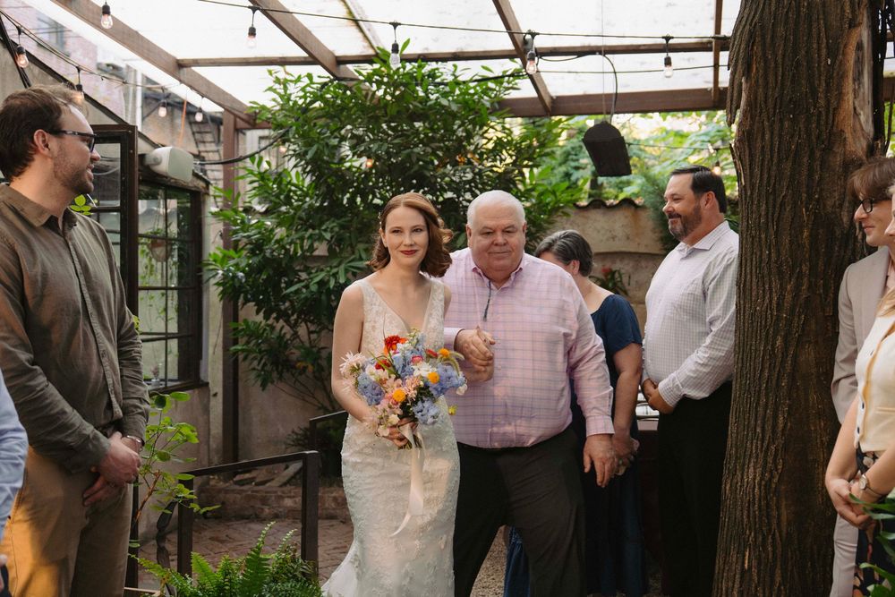 Outdoor wedding celebration under a covered patio with natural tree elements.
