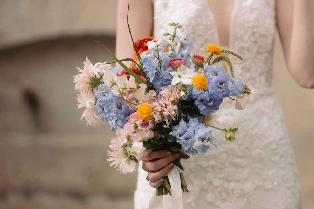 Colorful spring bouquet with daisies and blue flowers against a white lace background.