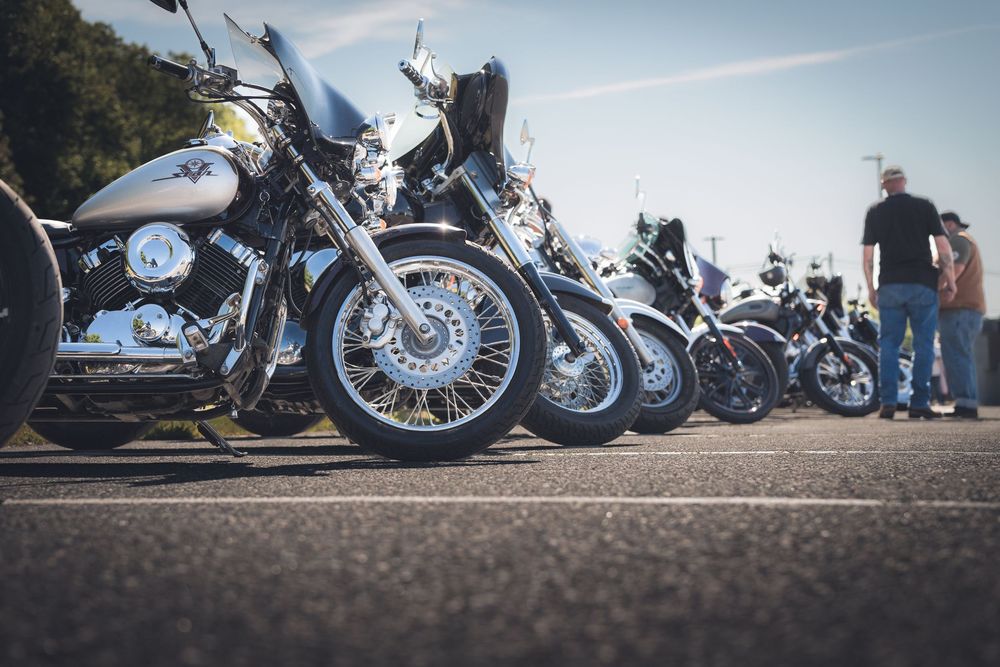 Row of parked motorcycles lined up at a motorcycle event or gathering.