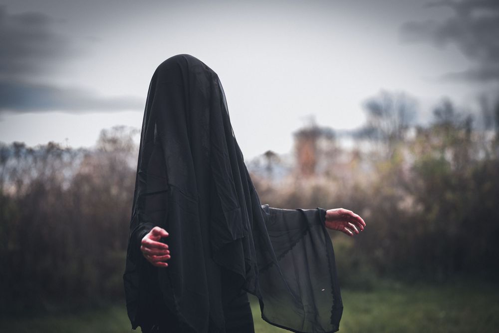 Silhouette of a figure in flowing black clothing against a moody sky.