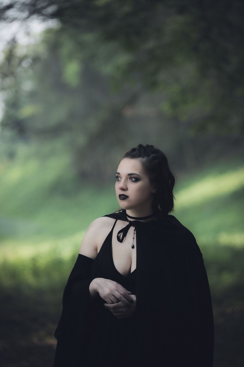 Gothic-styled portrait in a forest setting with dramatic lighting.