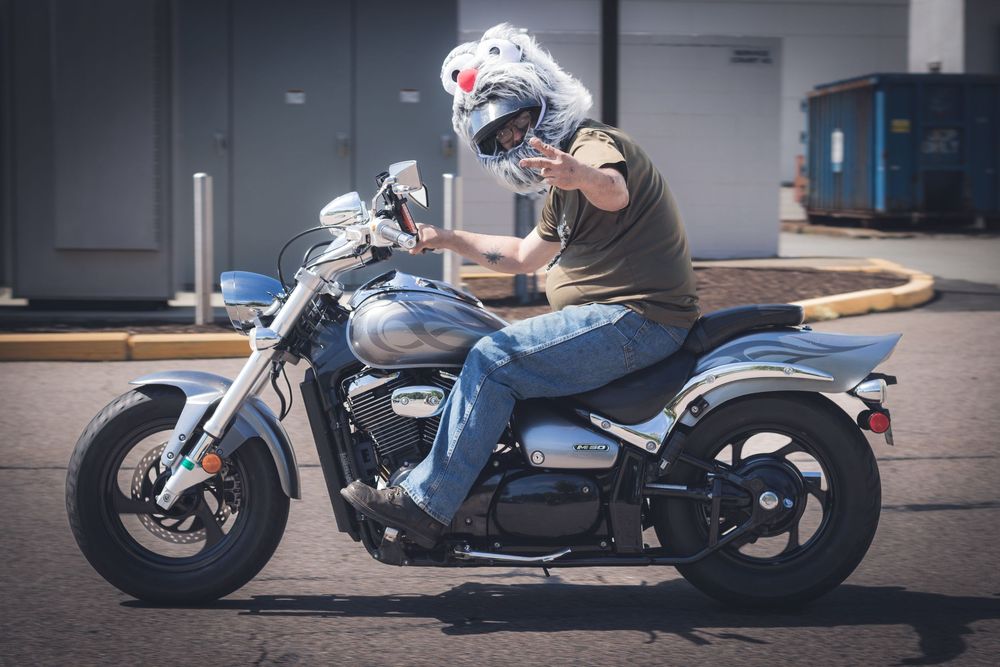 A motorcycle rider on a blue cruiser bike in a parking lot.