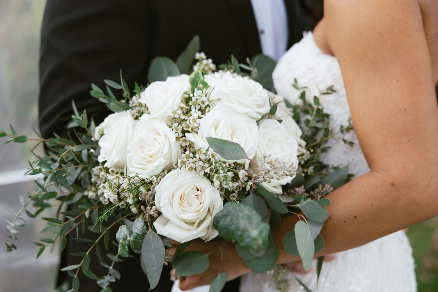 A collection of elegant white wedding bouquets with roses and eucalyptus greenery arranged in a row.