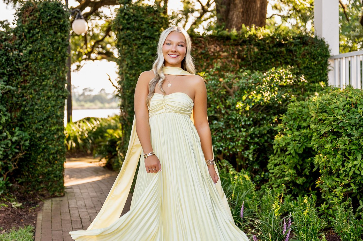 Portrait session on outdoor porch with white columns and lush garden backdrop.