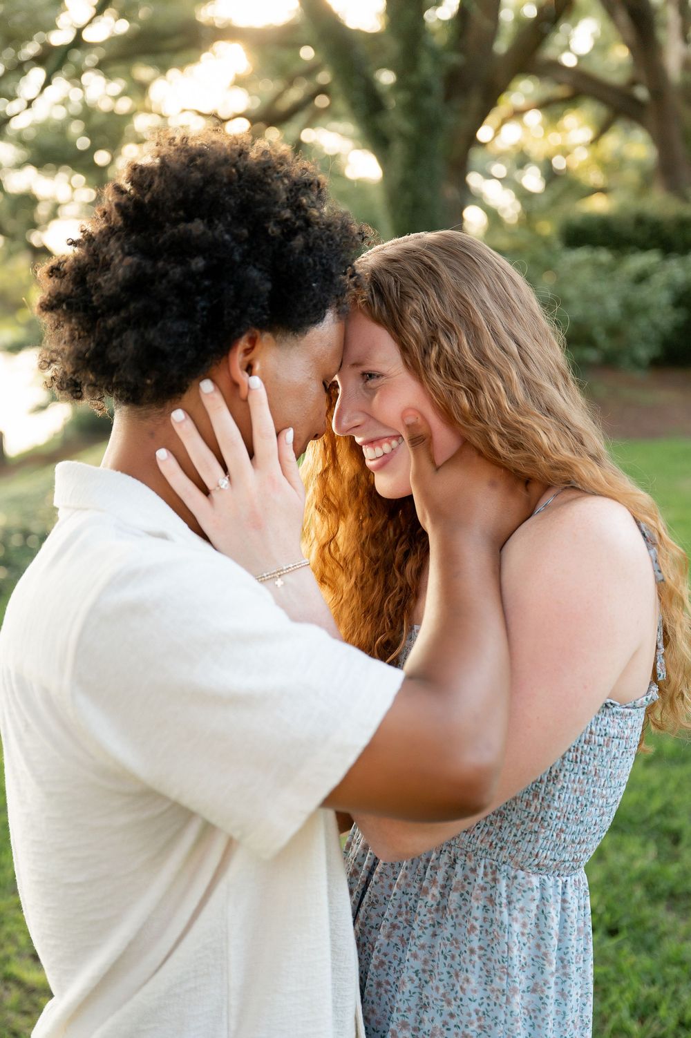An intimate moment between a couple in a white shirt and blue dress outdoors.
