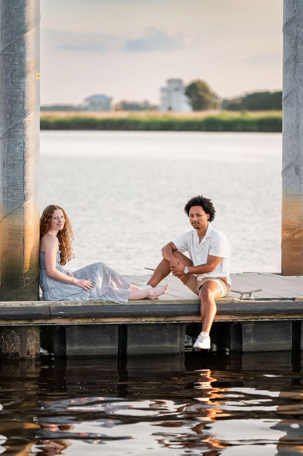 A couple relaxes on a waterfront dock during golden hour.