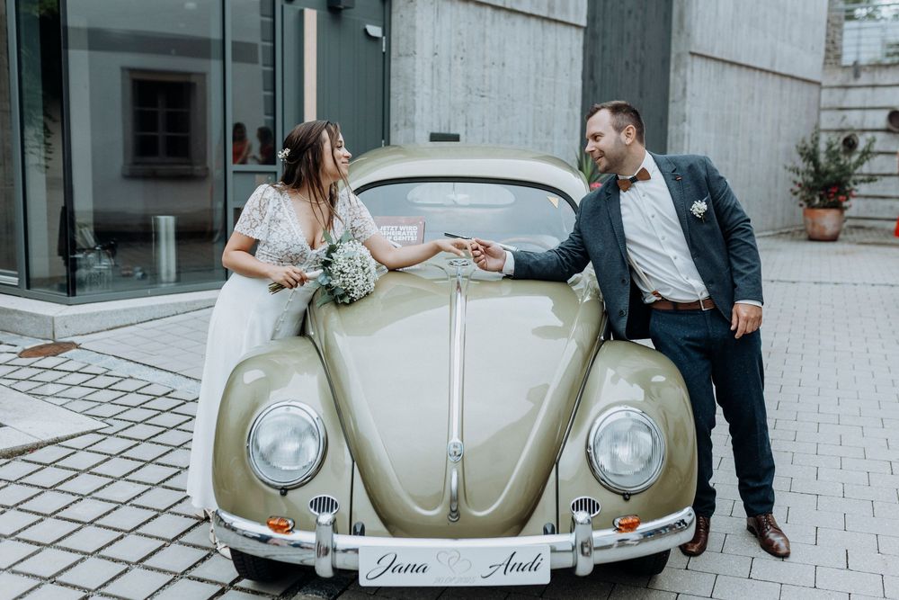 A classic beige Volkswagen Beetle parked outside as a wedding car.
