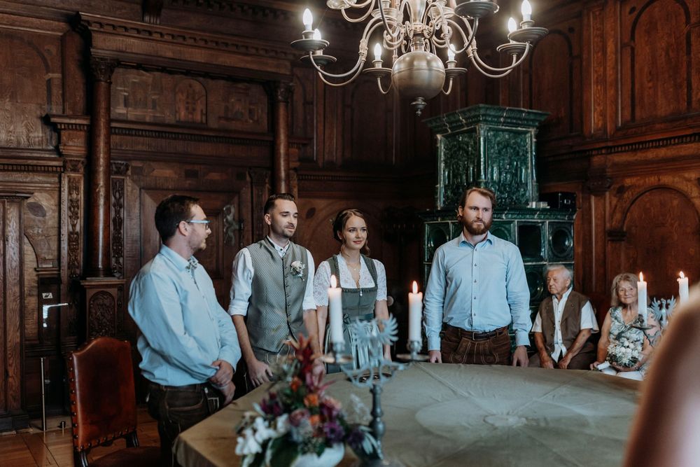 Wedding reception in dark wooden hall with elegant chandeliers.