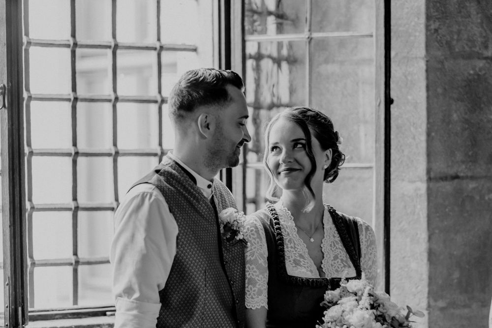 A romantic black and white wedding moment captured by a window.