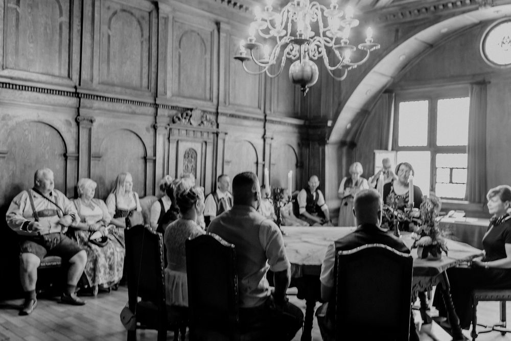 Black and white photo of guests seated at formal dinner in an ornate hall.