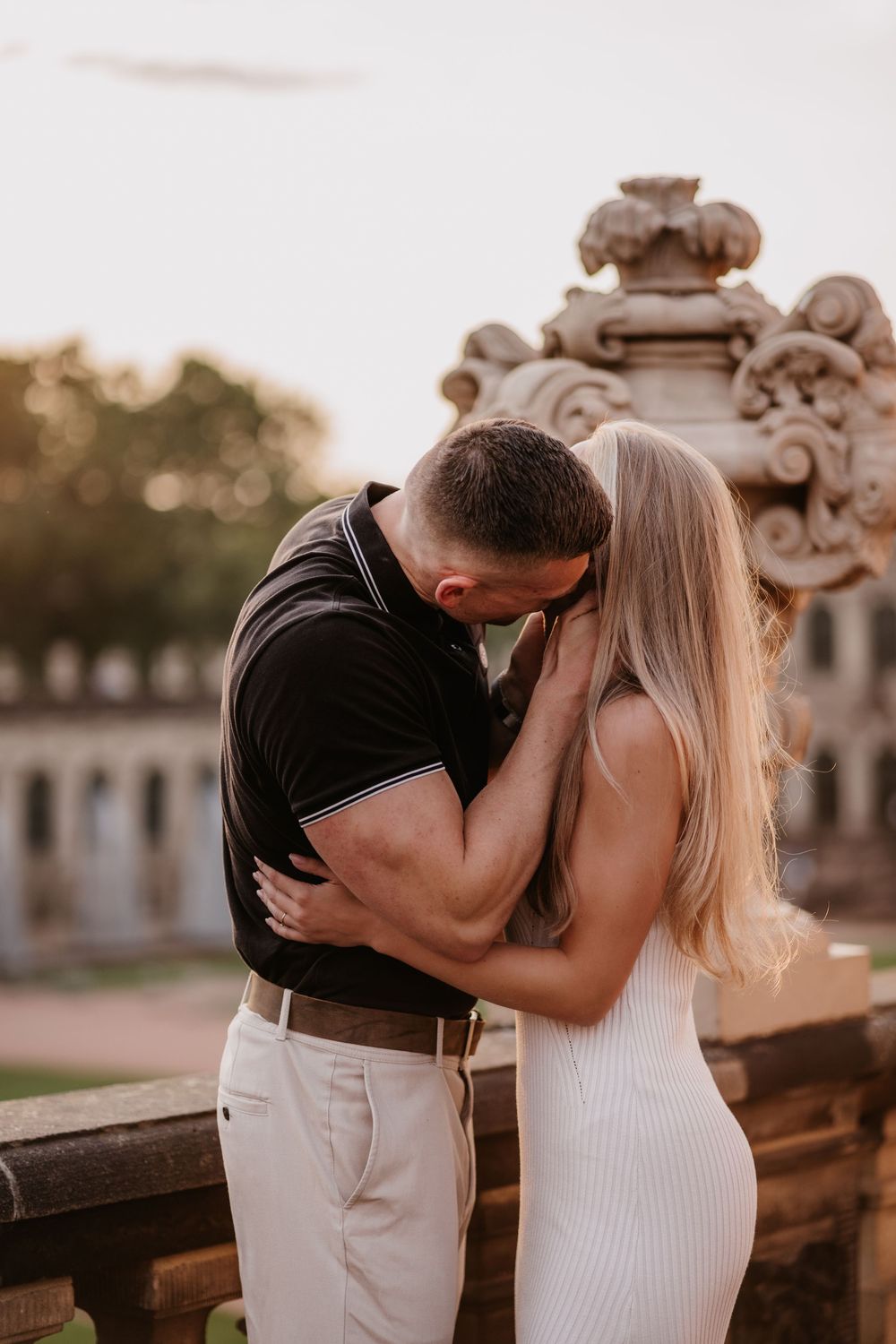 A romantic couple embraces at sunset near ornate architectural columns in a series of intimate photos.